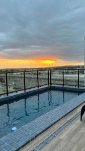 een zwembad met een zonsondergang op de achtergrond bij Flat em Intermares Beach in Cabedelo