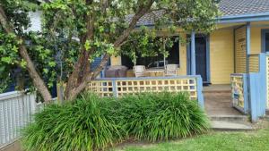 Un porche de una casa con una valla y un árbol. en Winda Woppa Magic, en Hawks Nest