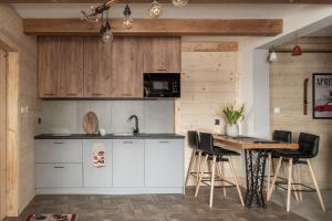 a kitchen with white cabinets and a table with chairs at Tatra Prime in Bukowina Tatrzańska