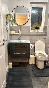 a bathroom with a toilet and a sink and a mirror at Modern 2-Bed Flat, Spacious, near Harry Potter Studio in Watford