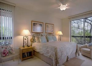 a bedroom with a bed and a chair and windows at Golf-view condo with golf discounts & lanai in Waikoloa
