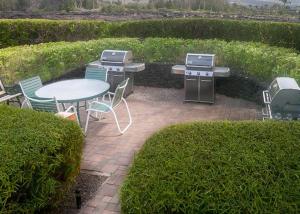 a patio with a table and a grill and chairs at Golf-view condo with golf discounts & lanai in Waikoloa
