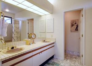 a bathroom with two sinks and a large mirror at Golf-view condo with golf discounts & lanai in Waikoloa