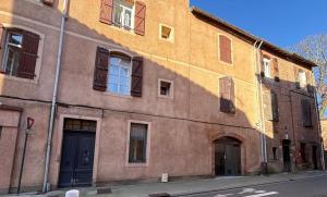 ein großes Backsteingebäude mit Fenstern und einer blauen Tür in der Unterkunft Le Rinaldi Loft in Albi