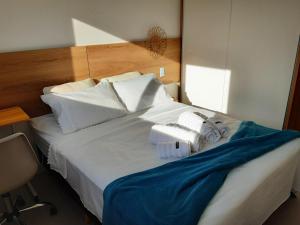 een slaapkamer met een wit bed met handdoeken erop bij Quarto e banheiro privativo pet friendly in Garopaba