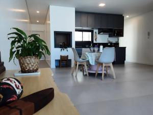 een woonkamer en een keuken met een tafel en stoelen bij Quarto e banheiro privativo pet friendly in Garopaba +12 foto's