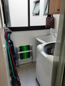 een kleine keuken met een wasmachine en een raam bij Quarto e banheiro privativo pet friendly in Garopaba