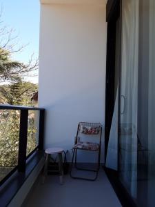 een stoel op een balkon naast een raam bij Quarto e banheiro privativo pet friendly in Garopaba