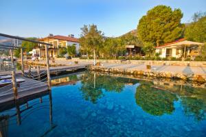 ein Pool mit blauem Wasser, einem Dock und Gebäuden in der Unterkunft Losta Sahil Evi - Adults Only +12 in Selimiye