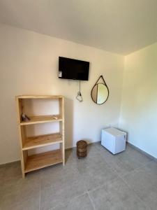 een kamer met een plank en een tv aan de muur bij Pousada Vila Mar Japaratinga in Japaratinga