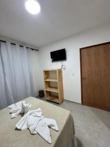 een slaapkamer met een bed met witte kleren erop bij Pousada Vila Mar Japaratinga in Japaratinga