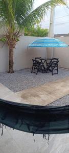 een picknicktafel en een blauwe parasol naast een palmboom bij Matinhos balneário Riviera in Matinhos