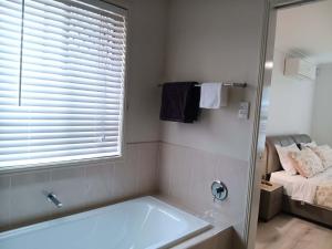 a bathroom with a tub and a window and a bed at Victoria Point King bed room & Breakfast in Victoria Point