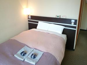 a hotel room with a bed with two towels on it at Hotel Furukawa Hills in Osaki