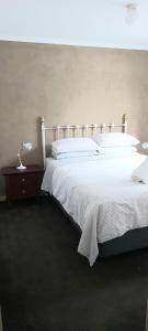 een slaapkamer met een groot wit bed en een nachtkastje bij Margarets Lane in Warrnambool