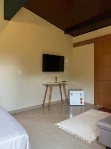 Camera con TV a parete e tavolo di chalé cilla a Caparaó Velho