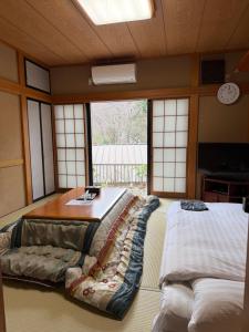 a room with a bed and a table and windows at 箱根宿燕帰 in Hakone +43 photos
