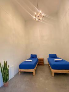 zwei Betten in einem Zimmer mit blauen Laken und einem Kronleuchter in der Unterkunft El Pinche Hostal in Guadalajara
