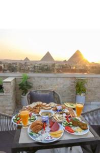 een tafel met borden met voedsel met piramides op de achtergrond bij Pyramids View Hotel in Caïro