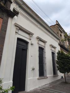 ein weißes Gebäude mit schwarzen Fenstern in der Unterkunft El Pinche Hostal in Guadalajara