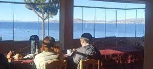 twee mensen aan een tafel met uitzicht op de oceaan bij SUMAQ WASI LLACHON casa de Juana in Llachon
