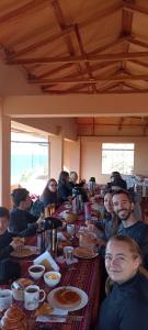 een groep mensen die aan een lange tafel eten bij SUMAQ WASI LLACHON casa de Juana in Llachon