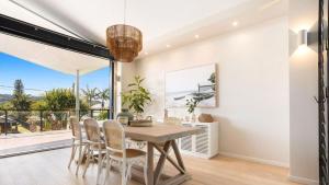a dining room with a table and chairs and a large window at Luxury On The Bay - Wanda in Suffolk Park