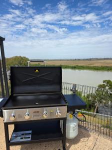 a grill on a porch with a view of a river at RiverBed Rise in Tailem Bend