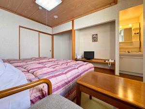 a bedroom with a bed and a table in it at Hakuba Tsugaike Sunrise Tanne in Otari