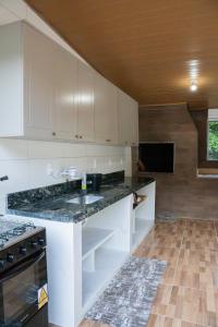 een keuken met witte kasten en een zwart aanrechtblad bij Casa Alemã Alfredo Wagner SC in Alfredo Wagner