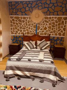 a bedroom with a large bed with a wall at Momo Surf Housse in Wassane