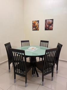 een eettafel met vier stoelen en een groene tafel bij Homestay 76 in Mersing