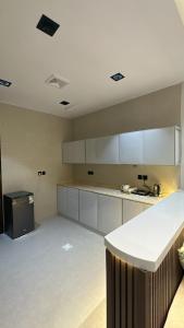 una grande cucina con mobili bianchi e un bancone di بيتك الثاني a Abha