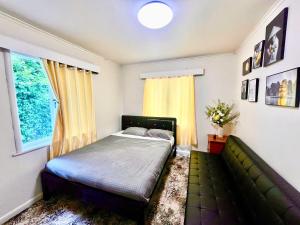 a bedroom with a bed and a couch and a window at PRIVATE ROOMS IN CENTRAL AUCKLAND in Auckland