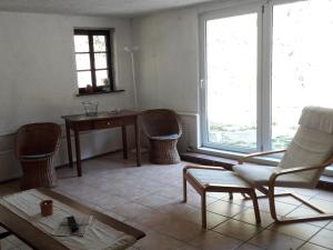 een woonkamer met een stoel, een tafel en ramen bij Main building Neumühle in Lutzerath