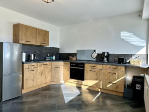 een keuken met houten kasten en een roestvrijstalen koelkast bij Dream holiday apartment Kinzig-Chalet in Schenkenzell