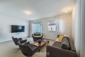 een woonkamer met een bank, stoelen en een tafel bij Casa c/ Piscina e 6 Quartos PJE0001 in Barra de Jacuípe