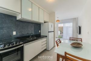 een keuken met witte kasten en een tafel met een wastafel bij Casa c/ Piscina e 6 Quartos PJE0001 in Barra de Jacuípe