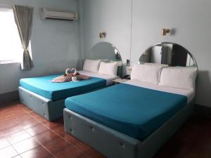 two beds sitting next to each other in a room at Anodard Hotel in Nakhon Sawan