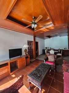 un soggiorno con ventilatore a soffitto e TV di P House CNX a Chiang Mai