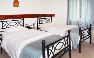 two beds in a bedroom with white sheets at Arusha Naaz Hotel in Arusha