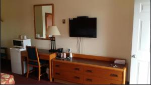 a hotel room with a desk and a television on the wall at River Mist INN in Sturgeon Falls