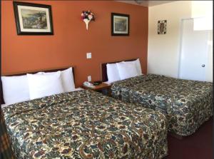 two beds in a hotel room with orange walls at River Mist INN in Sturgeon Falls