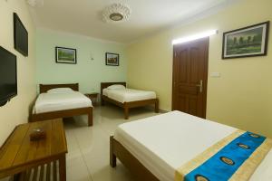 a hotel room with two beds and a tv at La Villa 23 Signature in Siem Reap