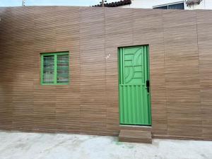 a wooden wall with a green door and two windows at PNZ Loft 2 in Petrolina