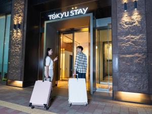 a man and woman standing outside of a building with luggage at Tokyu Stay Ginza in Tokyo