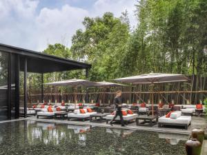 - une femme qui se promène au bord d'une piscine avec des chaises et des parasols dans l'établissement The PuLi Shanghai, à Shanghai