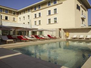 a hotel with a swimming pool with chairs and a building at Mercure Avignon TGV Hotel & Spa in Avignon