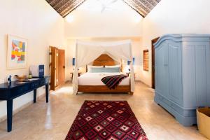 a bedroom with a bed with a dresser and a desk at Shelter Island in Ubud