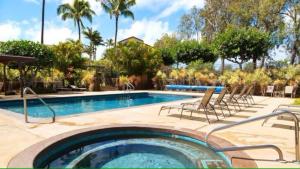 a swimming pool with lounge chairs and a swimming pool at Tropical condo with pools lanai & BBQ in Waikoloa Village